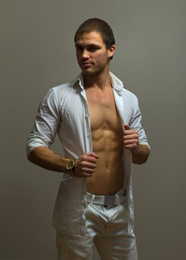 Kaslı erkek model gri arka plan üzerinde poz.