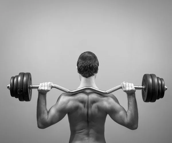 Homme musclé faisant des exercices avec haltère. Vue de derrière. Noir et blanc . — Photo