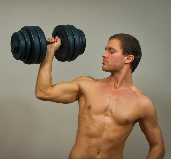 Handsome muscular male model with dumbbell. — Stock Photo, Image