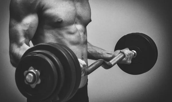 Muscular male model doing exercises with barbell. Black and white. — Stock Photo, Image