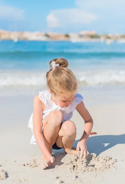 Liten flicka leker med sand på stranden. — Stockfoto
