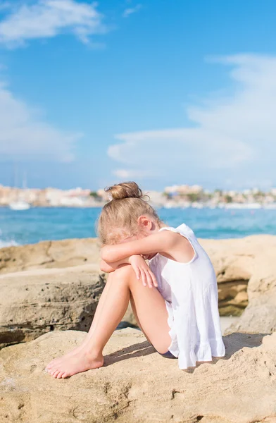 Sad little girl sitting on the beach. Place for text. — Stock Photo, Image