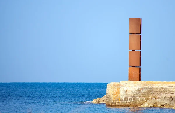 Vas-szobor közelében a kék tenger. — Stock Fotó