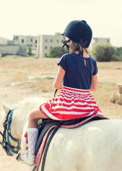 Portrait of little girl riding pony. From the back. — Stock Photo, Image