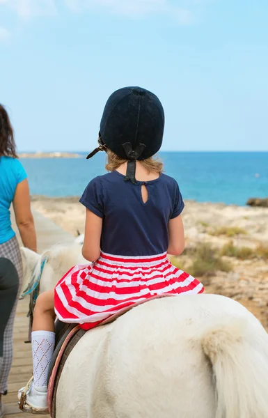 小女孩骑小马的画像。从背面. — 图库照片