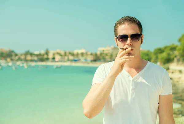 Чоловік у сонцезахисних окулярах палить сигару у відпустці . — стокове фото