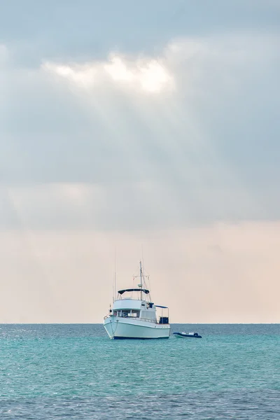 Iate branco no raio de luzes ao pôr do sol . — Fotografia de Stock