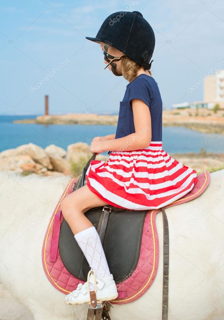 Portrait of little girl riding pony. 