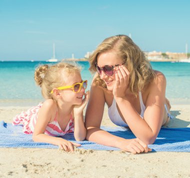 Mutlu kadın ve küçük kız sahilde.