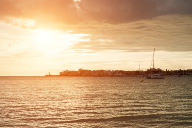 Deniz ve şehir üzerinde gün batımı. Sahilden fotoğraf.