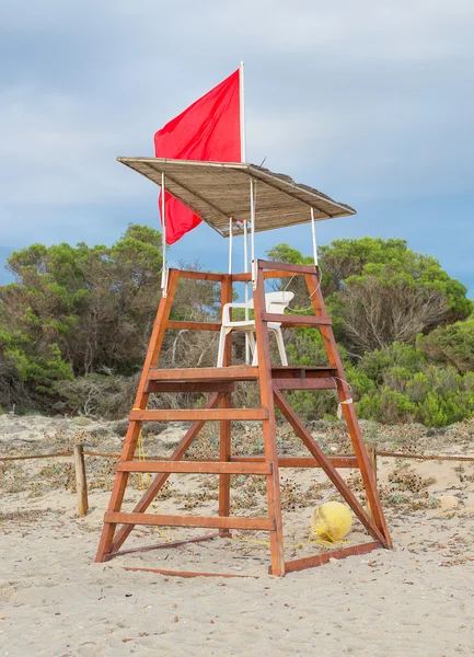 空的救生员塔与红旗插上海滩. — 图库照片