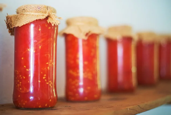 Konzervované rajčata ve sklenicích na dřevěné police. — Stock fotografie