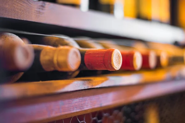 Garrafas de vinho empilhadas em prateleiras de madeira . — Fotografia de Stock