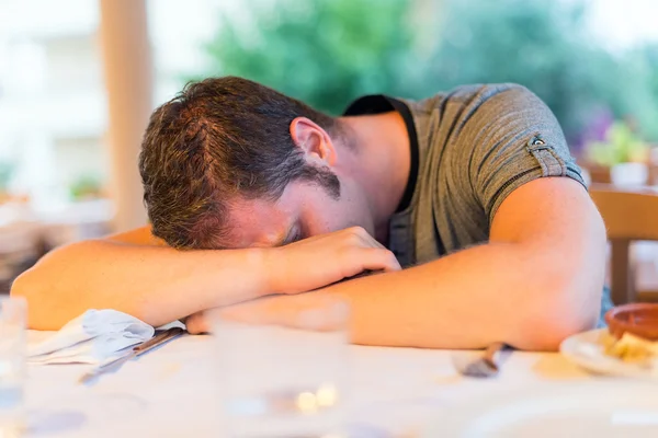 Dronken man viel in slaap op de tafel in restaurant. — Stockfoto