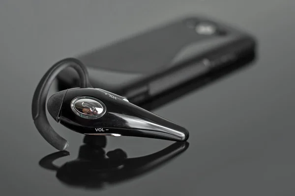 Close-up van handsfree bluetooth-apparaat in de buurt van mobiele telefoon. — Stockfoto