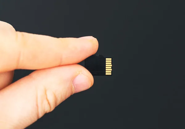 Männliche Hand hält Micro-SD-Karte auf schwarzem Hintergrund. — Stockfoto