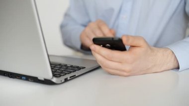 Cep telefonu ve dizüstü bilgisayar kullanan adam.