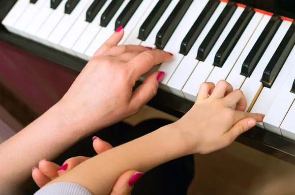 Mulher ensina a criança a tocar piano . — Fotografia de Stock