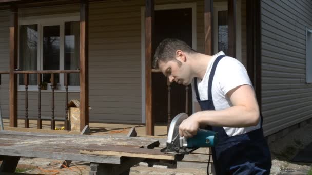 Handyman med handhållen såg maskin utomhus. — Stockvideo