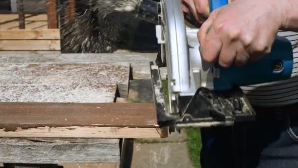 Handyman utilizando la máquina de sierra de mano al aire libre. — Vídeos de Stock