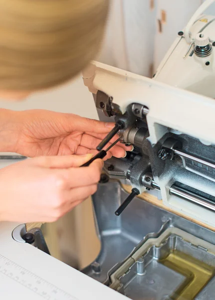 女手固定的缝纫机。维护. — 图库照片