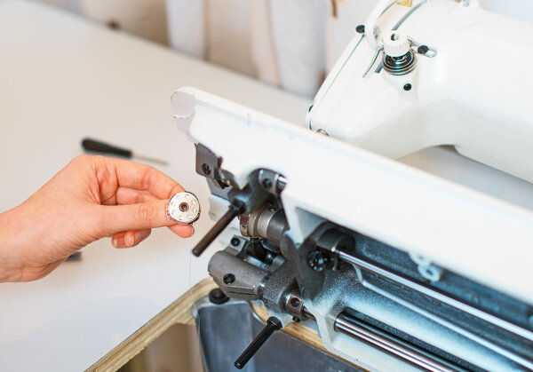 Female hand fixing sewing machine. Maintenance.