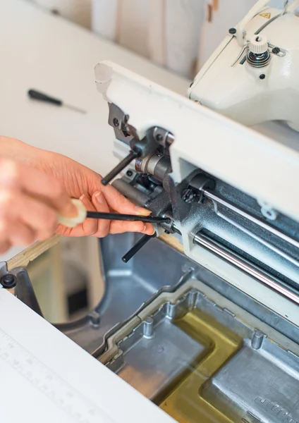 Female hand fixing sewing machine. Maintenance.