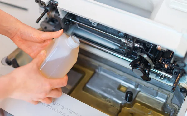 Female hand adding oil in sewing machine. Maintenance. — Stock Photo, Image