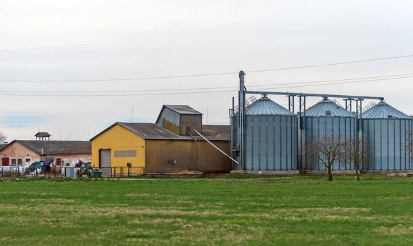 Fabriek en industriële silo's in de buurt van groene veld. — Stockfoto