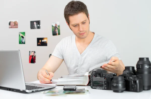 Mužské Fotograf sledovat fotoalbum na jeho pracovišti. — Stock fotografie