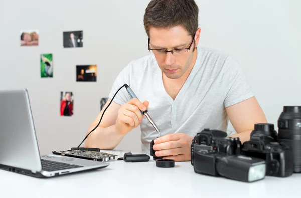 Male photographer soldering lens at his workplace. — Stock Photo, Image