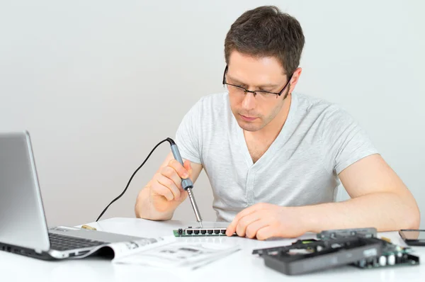 Técnico masculino soldando el router del interruptor del lan en su lugar de trabajo . — Foto de Stock