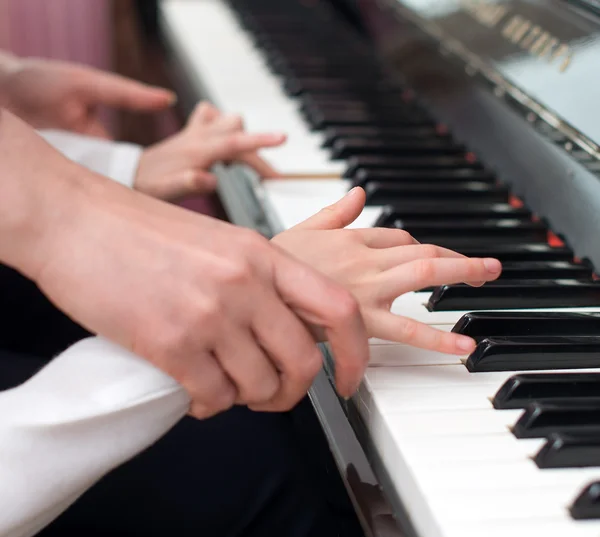 Donna che insegna alla bambina a suonare il pianoforte . — Foto Stock