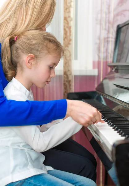 Vrouw onderwijs meisje om de piano te spelen. — Stockfoto