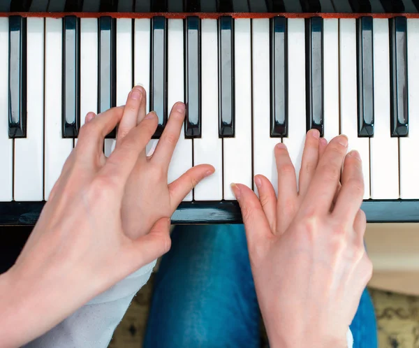 Vrouw onderwijs meisje om de piano te spelen. Bovenaanzicht. — Stockfoto