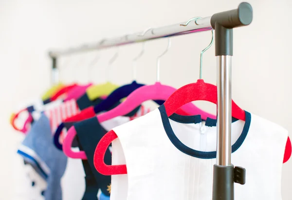 Lots of colorful dresses on hangers in shop. — Stock Photo, Image