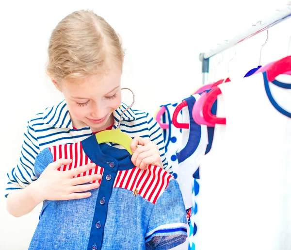 Маленька дівчинка вибирає плаття в магазині одягу . — стокове фото