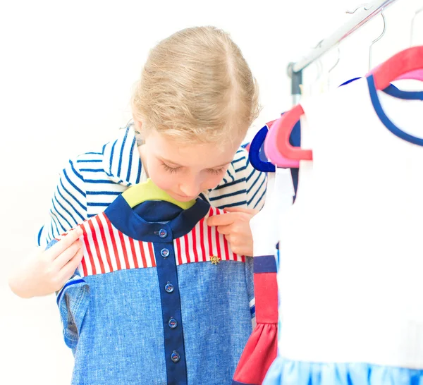 Little girl choosing dress in clothing store. — Stock Photo, Image