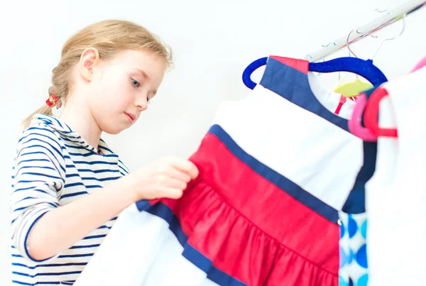 Маленька дівчинка вибирає плаття в магазині одягу . — стокове фото