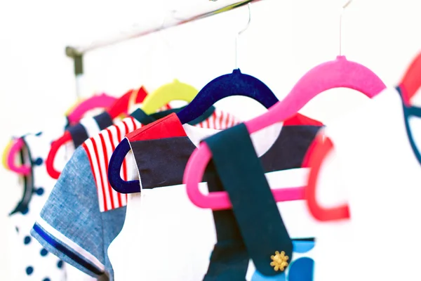 Lots of colorful dresses on hangers in shop. — Stock Photo, Image