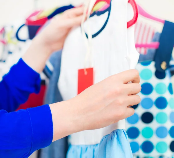 Ženská ruka výběr dětské oblečení v obchodě s oděvy. — Stock fotografie