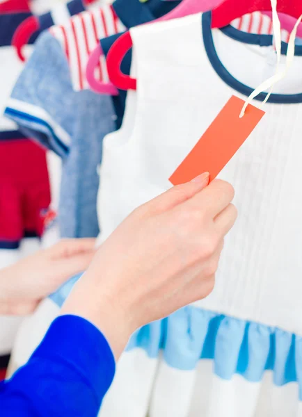 Mano della donna che sceglie vestito bambino al negozio di abbigliamento . — Foto Stock