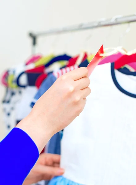 Рука жінки вибирає дитяче плаття в магазині одягу . — стокове фото