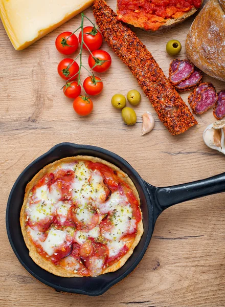 Draufsicht auf Pizza in eiserner Pfanne mit Zutaten. — Stockfoto