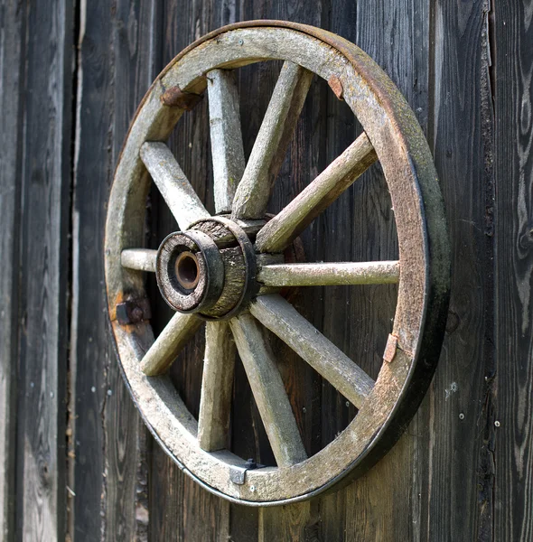 Old wooden carriage wheel hanging on the barn. Royalty Free Stock Photos