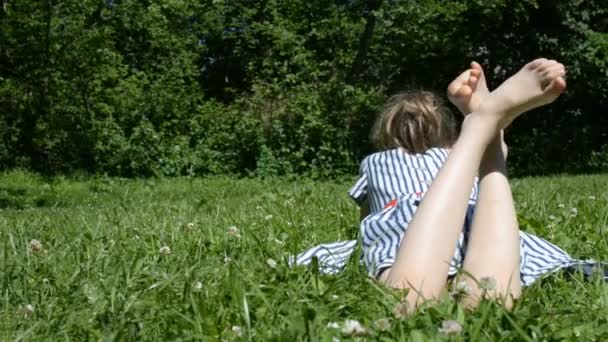 Niña acostada sobre hierba verde en el parque . — Vídeo de stock