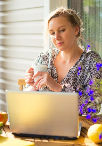 Frau mit Laptop im Garten im Urlaub. — Stockfoto