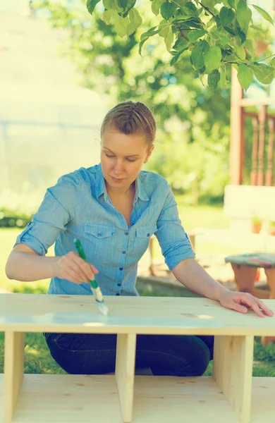 Mujer con pincel pintando muebles de madera . — Foto de Stock