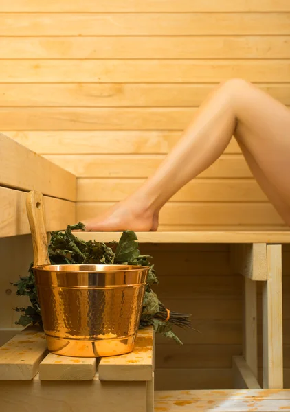 Wellnesszubehör in der Sauna. Frau im Hintergrund. — Stockfoto