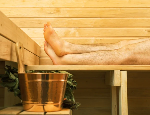 Lázeňské příslušenství v sauně. Muž v pozadí. — Stock fotografie